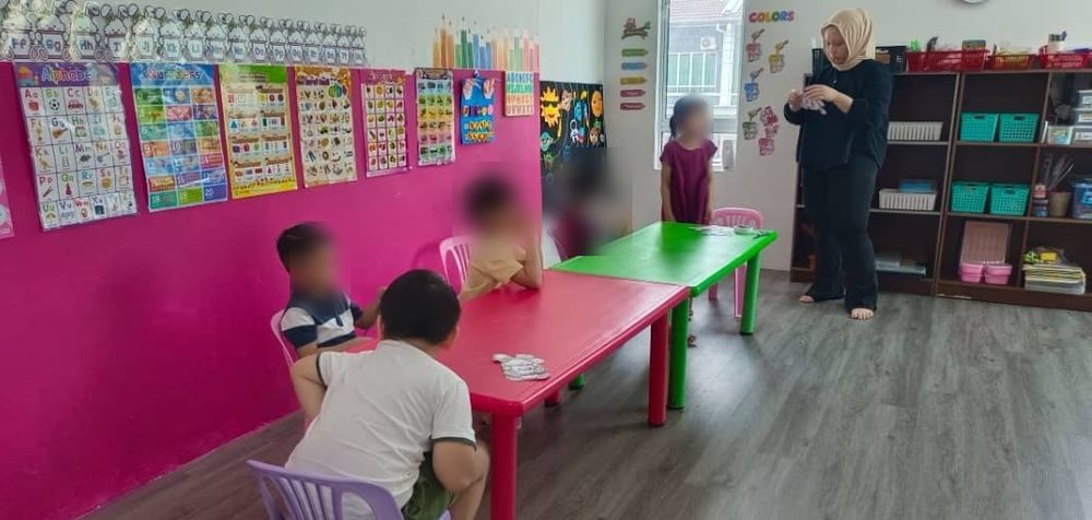 Children at a low table in the kindy classroom working through a matching-card activity with their teacher