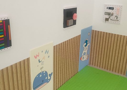 Quiet sensory corner with soft wall panels, tactile boards and a green play mat